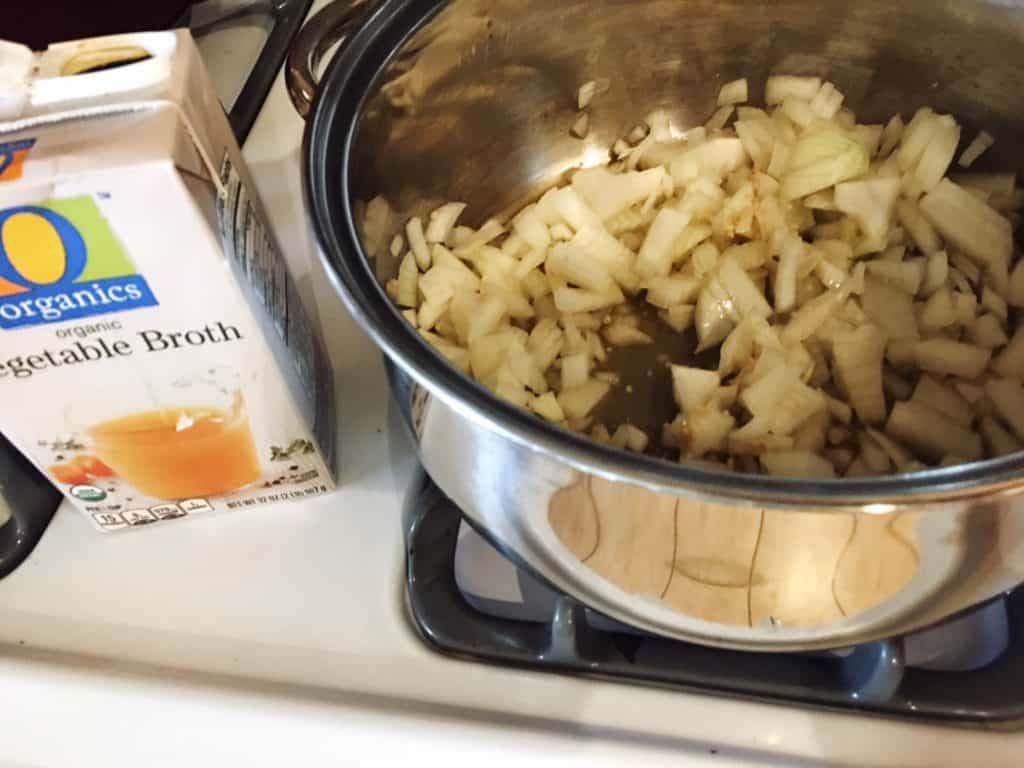 Onions Cooking in veggie broth in non stick pan for homemade pasta sauce
