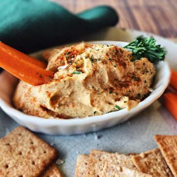 Oil free hummus in white dish with carrot sick