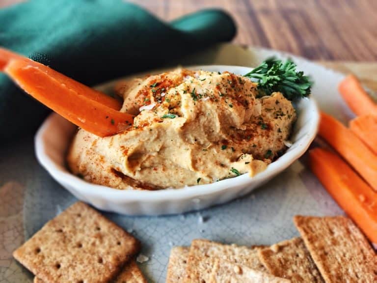 Oil free hummus in white dish with carrot sick
