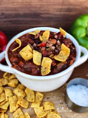 Chili in white bowl with corn chips and bell peppers