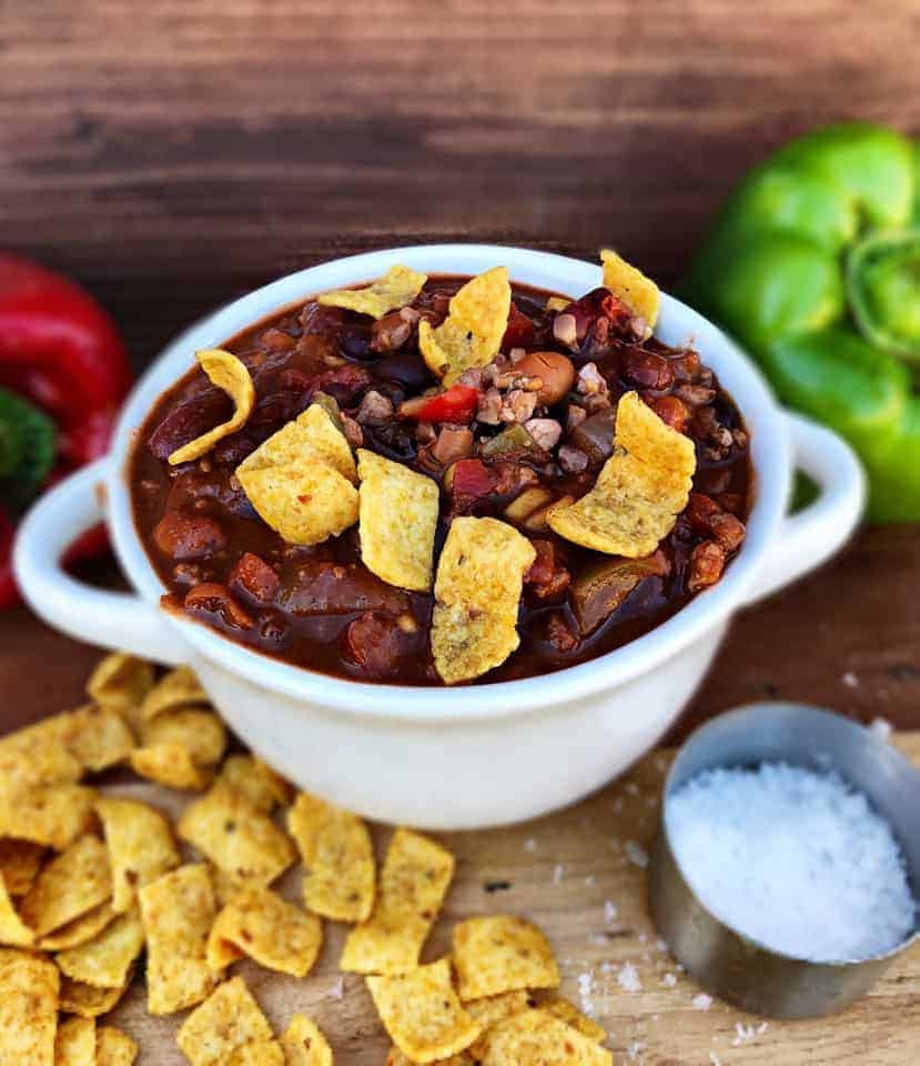 Chili in white bowl with corn chips and bell peppers