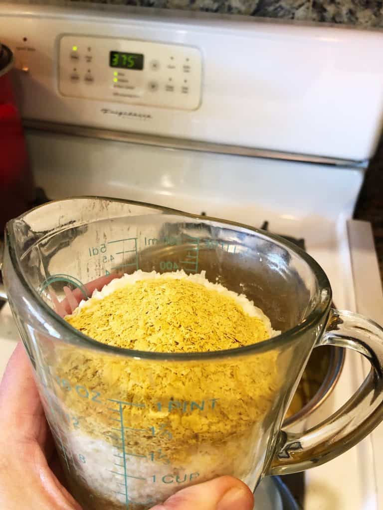 nutritional yeast and potato flakes in a measuring cup.