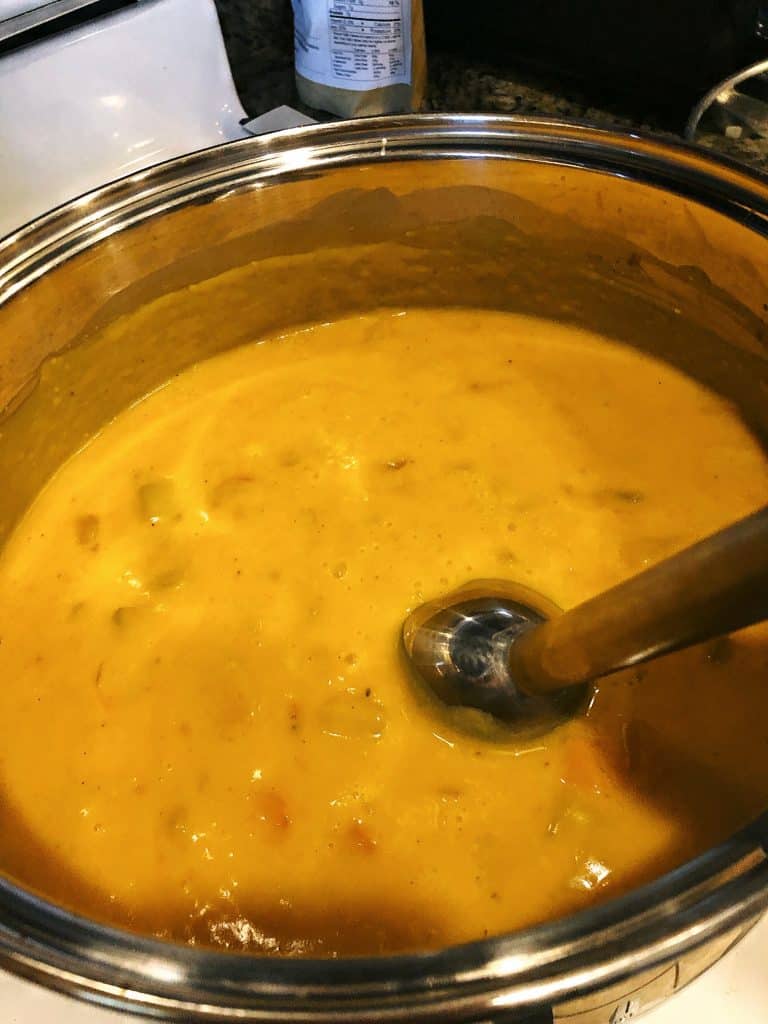 mixing butternut squash soup with a hand blender.