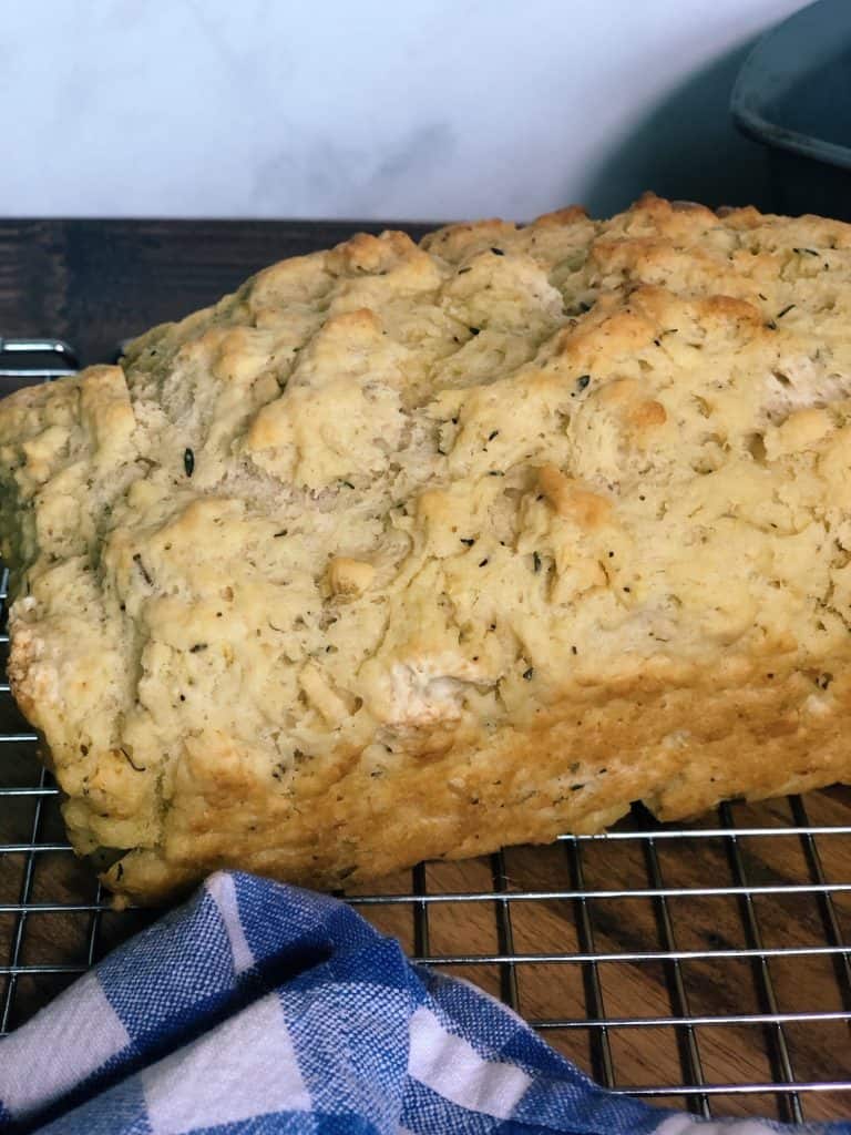 load of garlic herb beer bread with blue checkered napkin with loaf pan behind