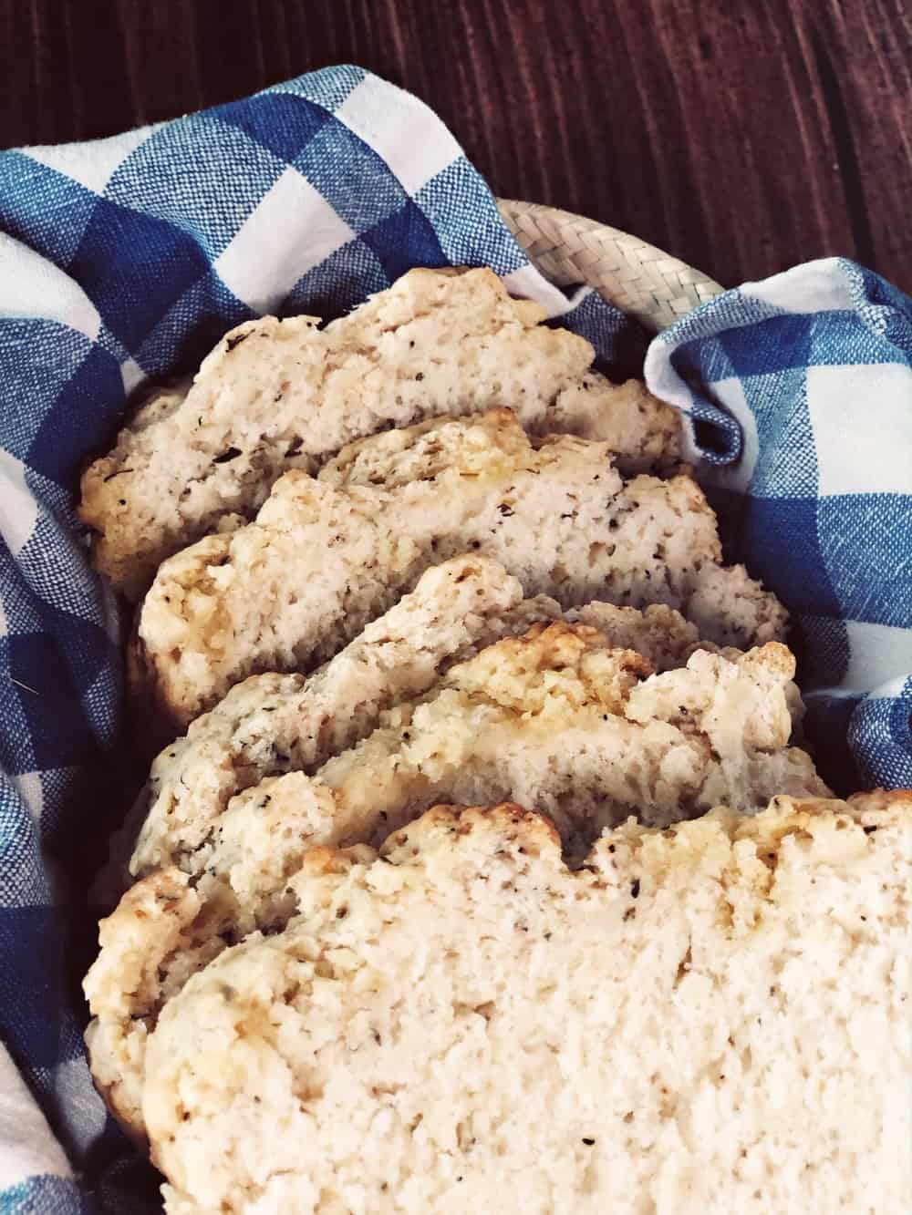 five slices of garlic herb beer bread in basket with blue checkered cloth