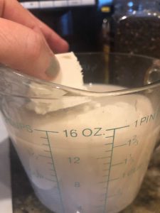 butter being placed in measuring cup with milk