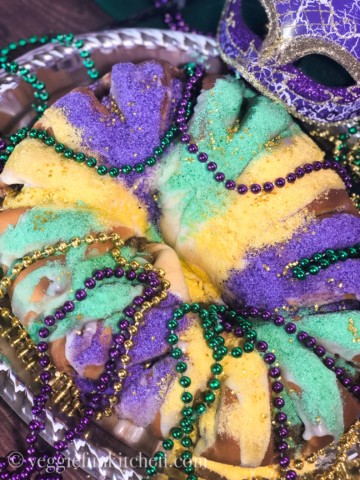 oval uncut king cake with beads and mask.