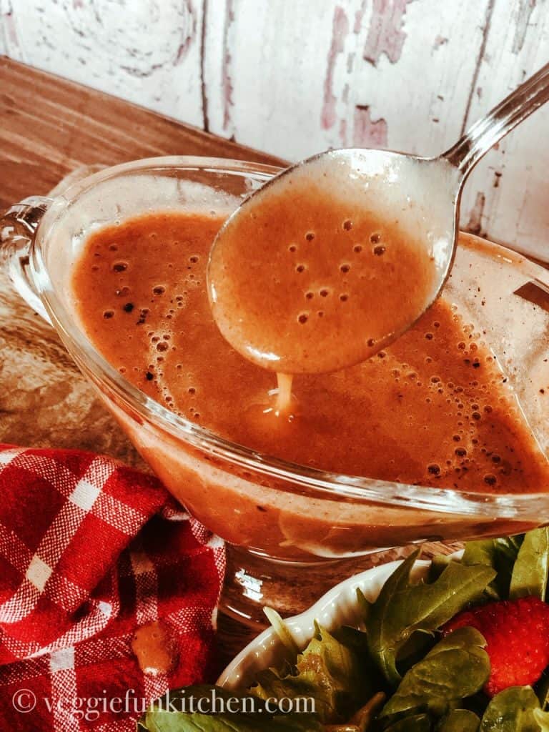 strawberry balsamic dressing in cup with spoon and strawberry salad