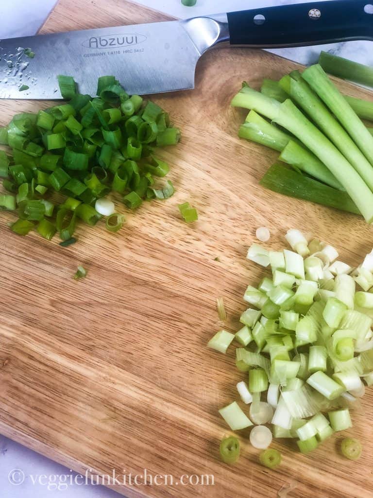 green onions sliced on a cutting board with knife