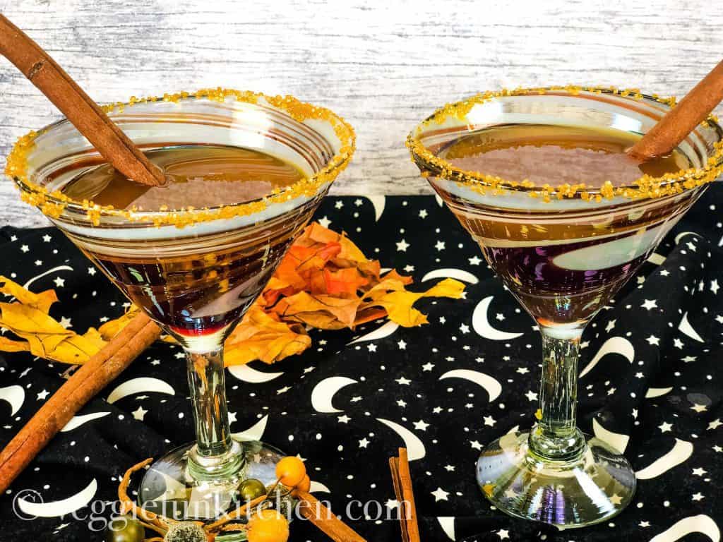 two pumpkin drinks in martini glasses with cinnamon sticks