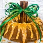 Pumpkin bundt cake on white plate with cinnamon stick and green rafia stem