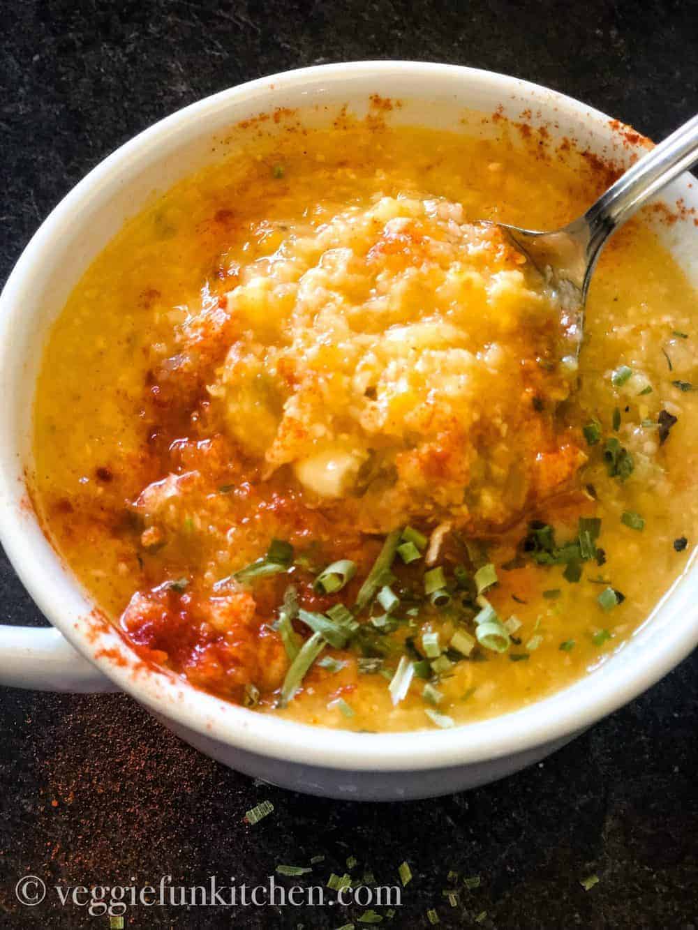 Corn chowder in white bowl with spoon dishing out a portion
