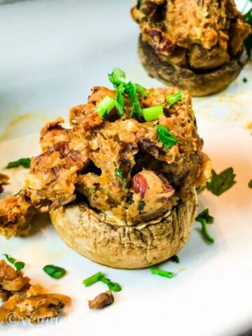 close up of two vegan stuffed mushrooms on white tray