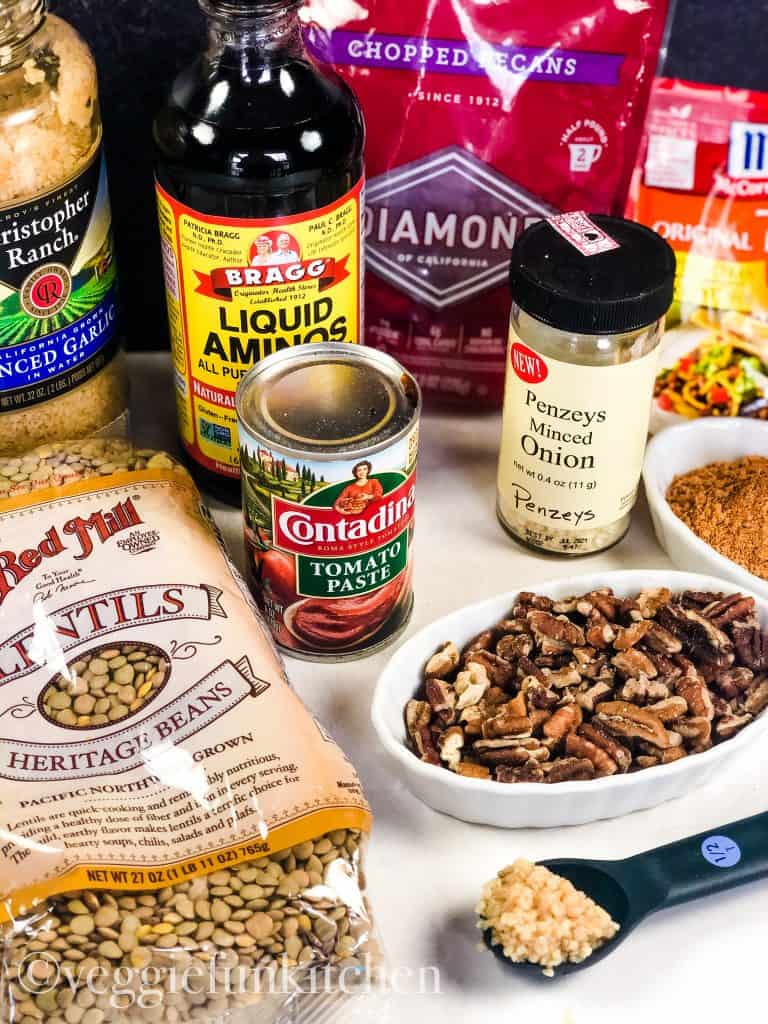ingredients for vegan taco meat including lentils, pecans, garlic, tomato paste, liquid aminos, minced onion, taco seasoning