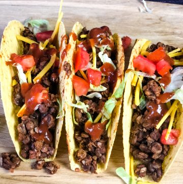 three tacos with vegan lentil taco meat on wooden board