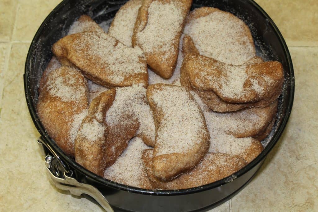 cut biscuits in bowl of cinnamon sugar