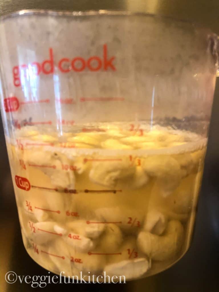 cashews soaking in hot water in measuring cup