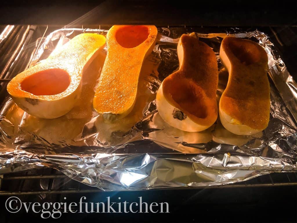 four butternut squash halves cooking in oven