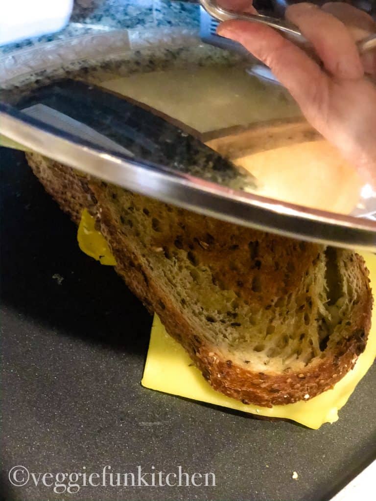 lid covering grilled cheese cooking on pan
