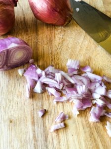 Chopped shallots on wooden cutting board
