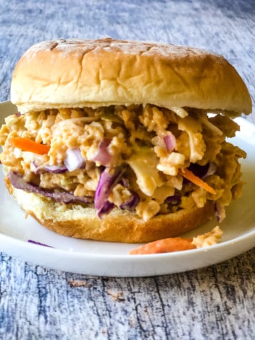 bbq chickpea salad sandwich with bun on white plate