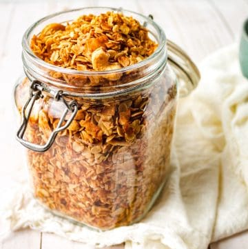 granola in glass jar with white napkin and green bowl