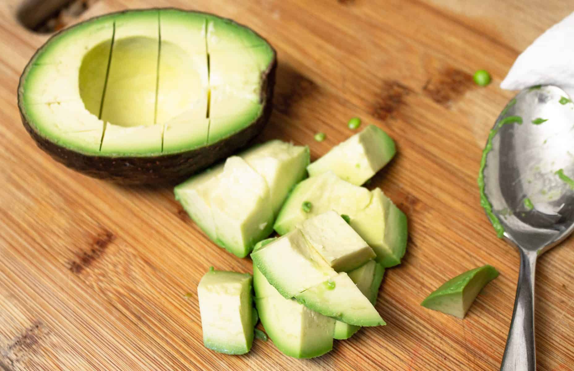 chopped avocado on cutting board with spoon
