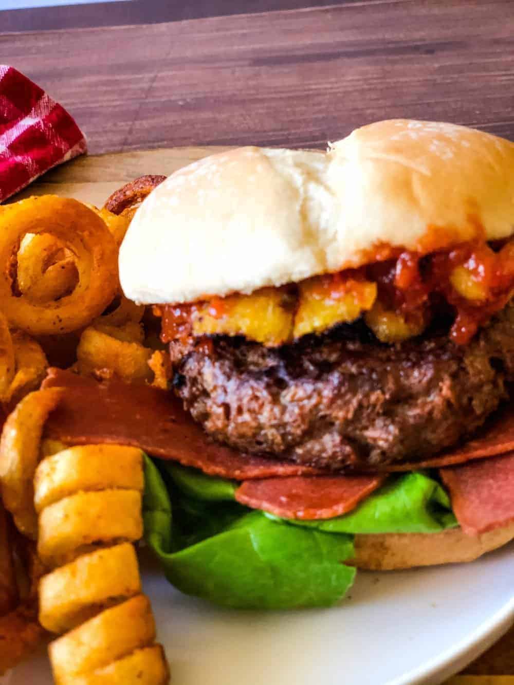 Hawaiian burger on plate with fries in background