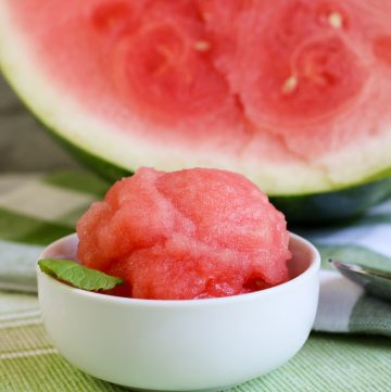 watermelon sorbet in white bowl with half watermelon and green checked cloth
