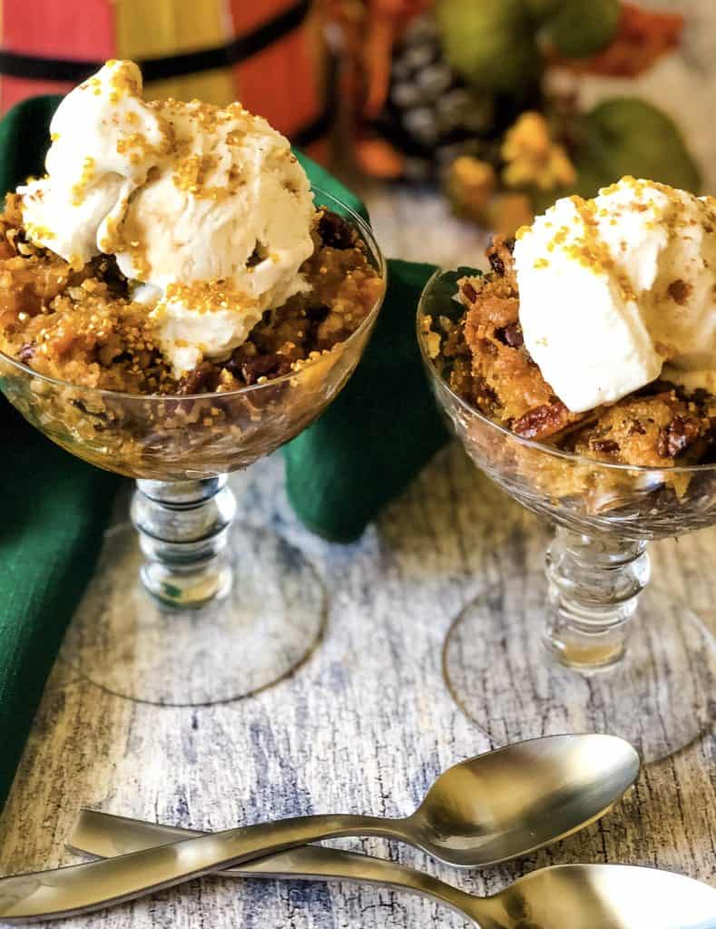 pumpkin dump cake in two glass goblets with vegan ice cream on top and seasonal decorations in background