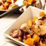 roasted butternut squash and cauliflower in white square dishes with sheet pan in background