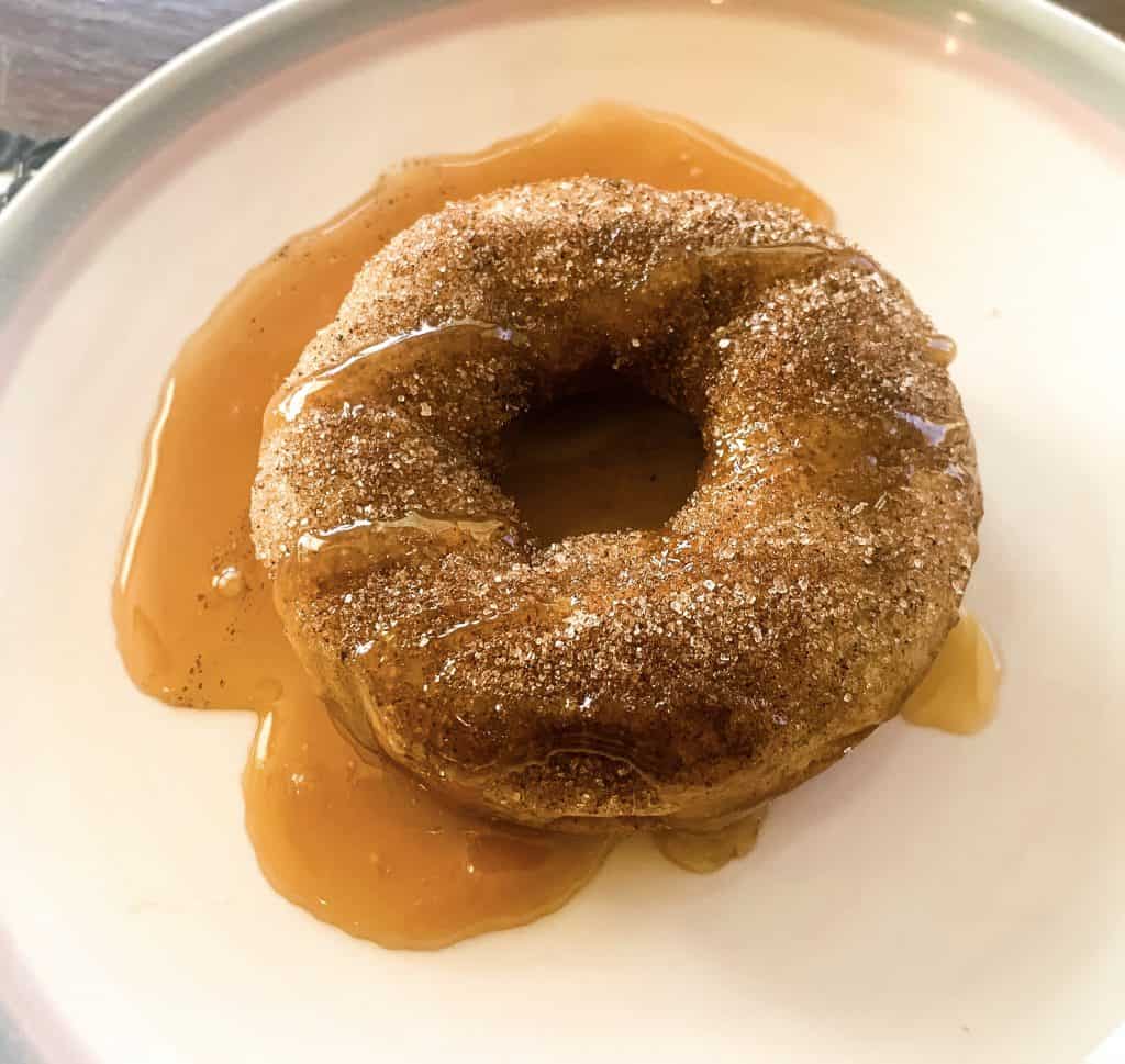 apple cider donut on plate with vegan caramel sauce drizzled on top