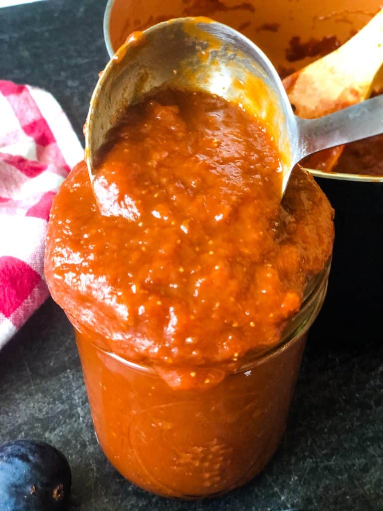 ladle dipping into glass jar of bourbon bbq sauce
