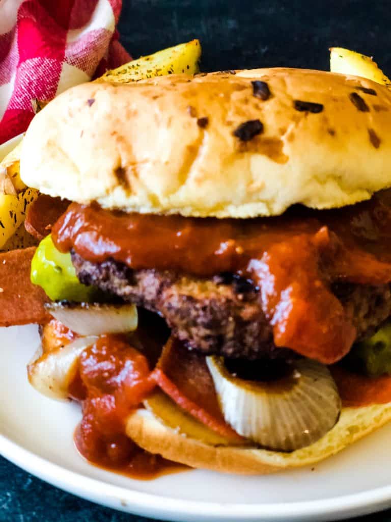 bourbon bbq sauce on burger with fried on white plate