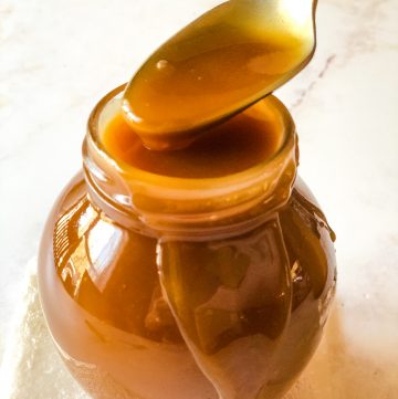 small jar of caramel sauce with spoon dipping in to scoop some out