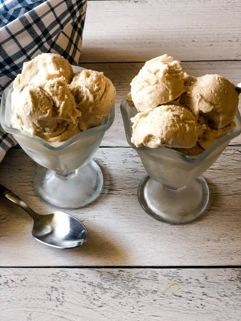 two glass ice cream dishes filled with sweet cream ice cream with blue plaid cloth in background