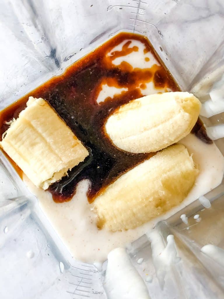 ingredients for sweet cream ice cream in a blender including cooked coconut milk, banana, and vanilla