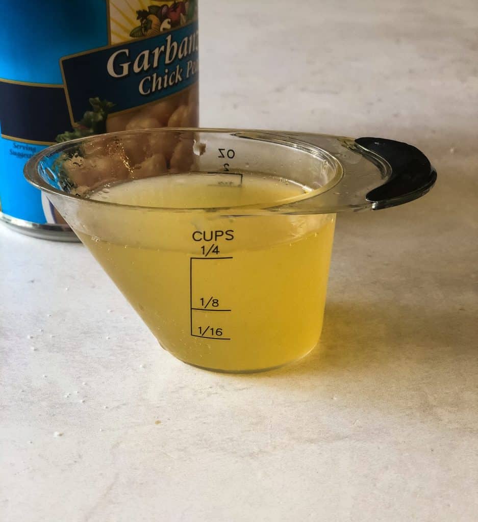 aquafaba in 1/4 measuring cup with canned garbanzo beans in background