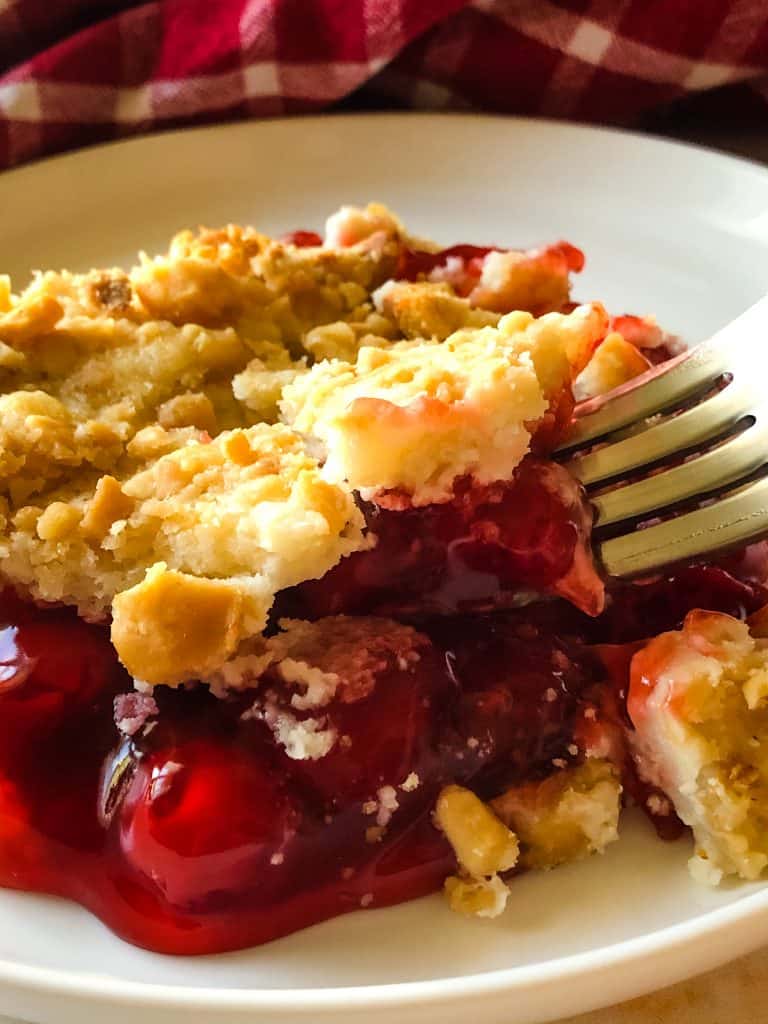 cherry cheesecake dump cake on plate with red checked napkin in background