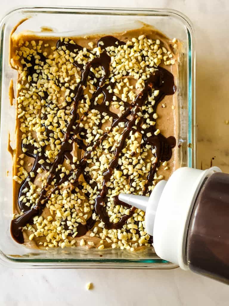 almond chocolate ice cream in glass container covered in chopped almonds and chocolate sauce