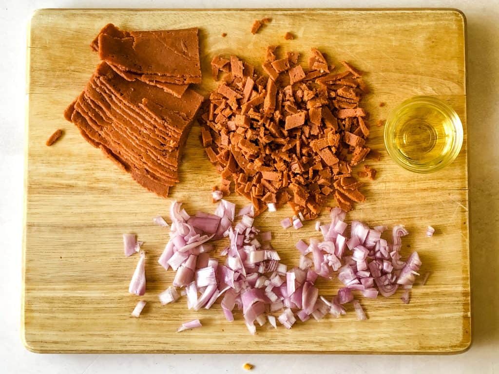 chopped onions and vegan bacon on cutting board with olive oil
