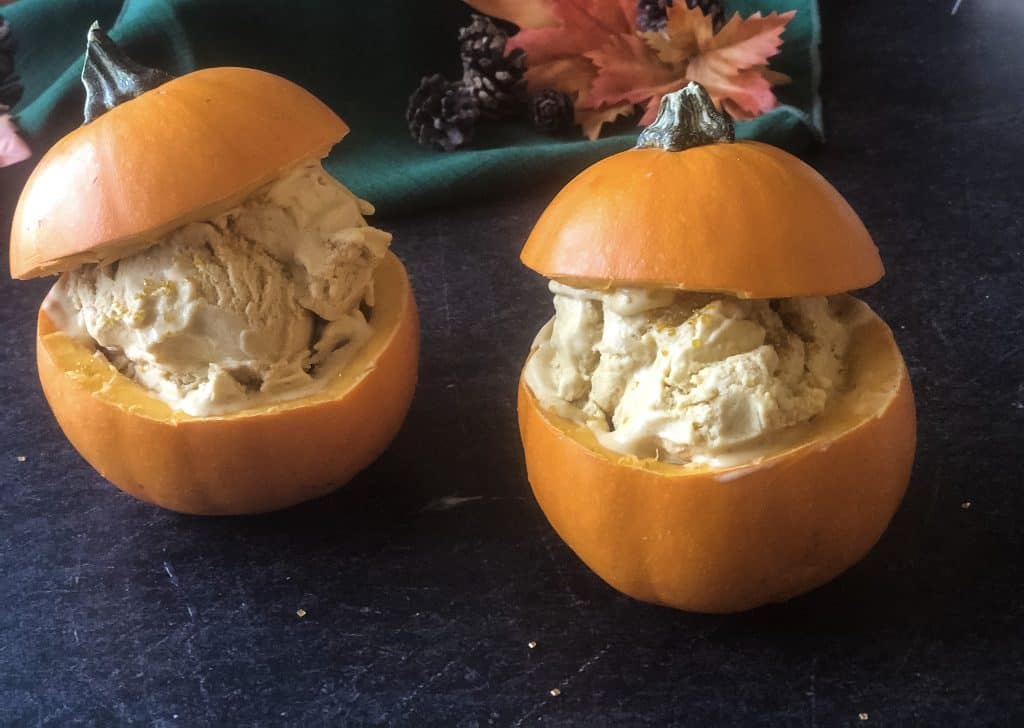 pumpkin ice cream in two little pumpkins with fall foliage in background