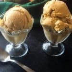 two glass ice cream dishes with pumpkin ice cream and pumpkins in background