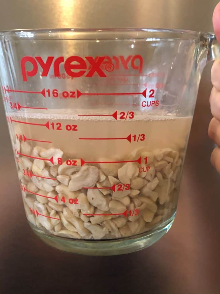 raw cashews soaking in water in glass measuring cup