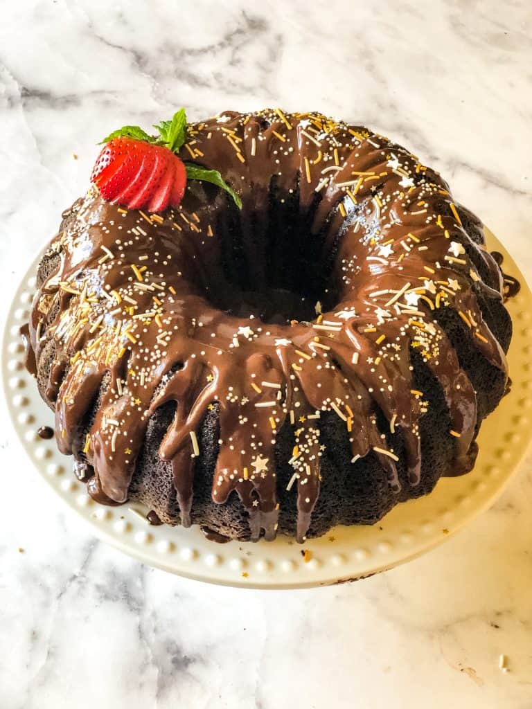 devils food cake frosted with ganache, sprinkles, and a cut strawberry