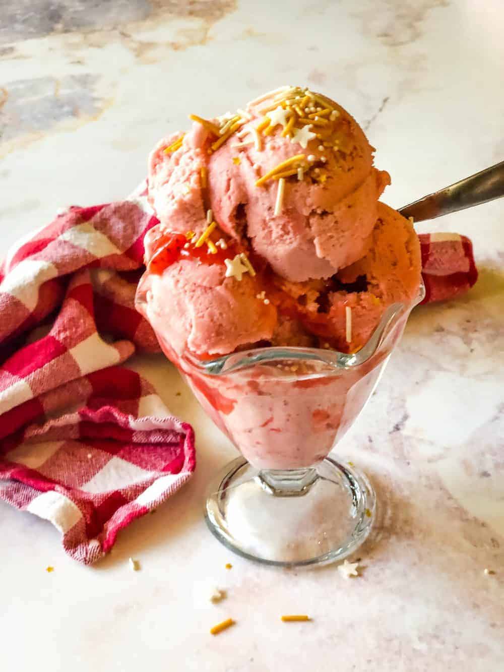 ice cream dish with scoops of strawberry banana ice cream and sprinkles on top