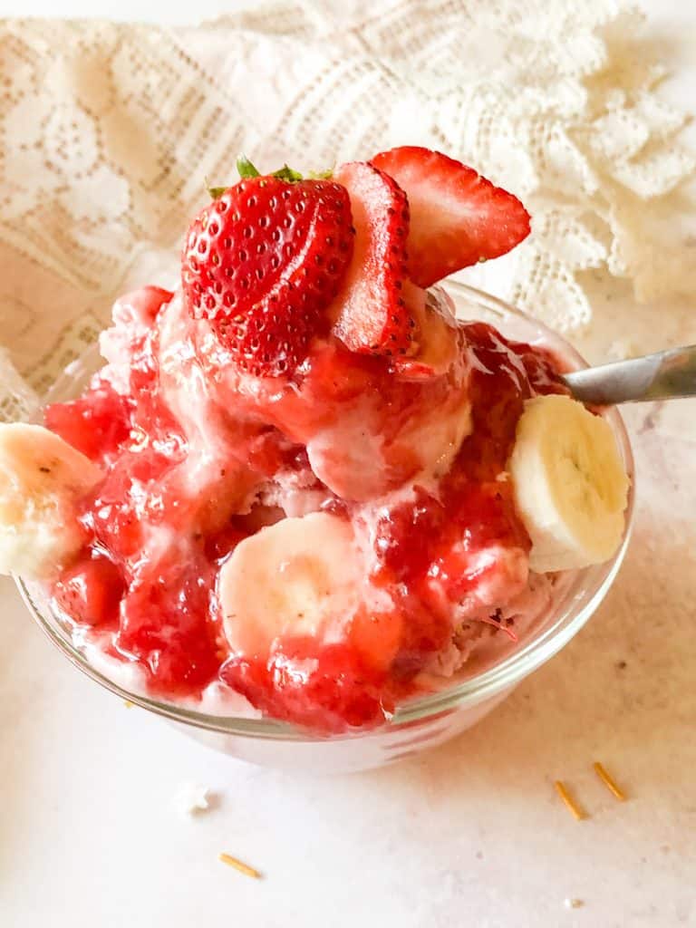 dish of strawberry banana ice cream with sliced strawberries and a luscious strawberry topping