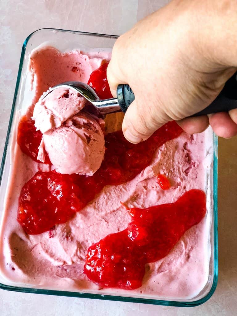 scooping out the strawberry ice cream showing stripes strawberry topping