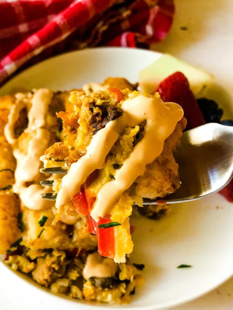 tater tot breakfast casserole with creamy sriracha sauce on top with bowl of fruit