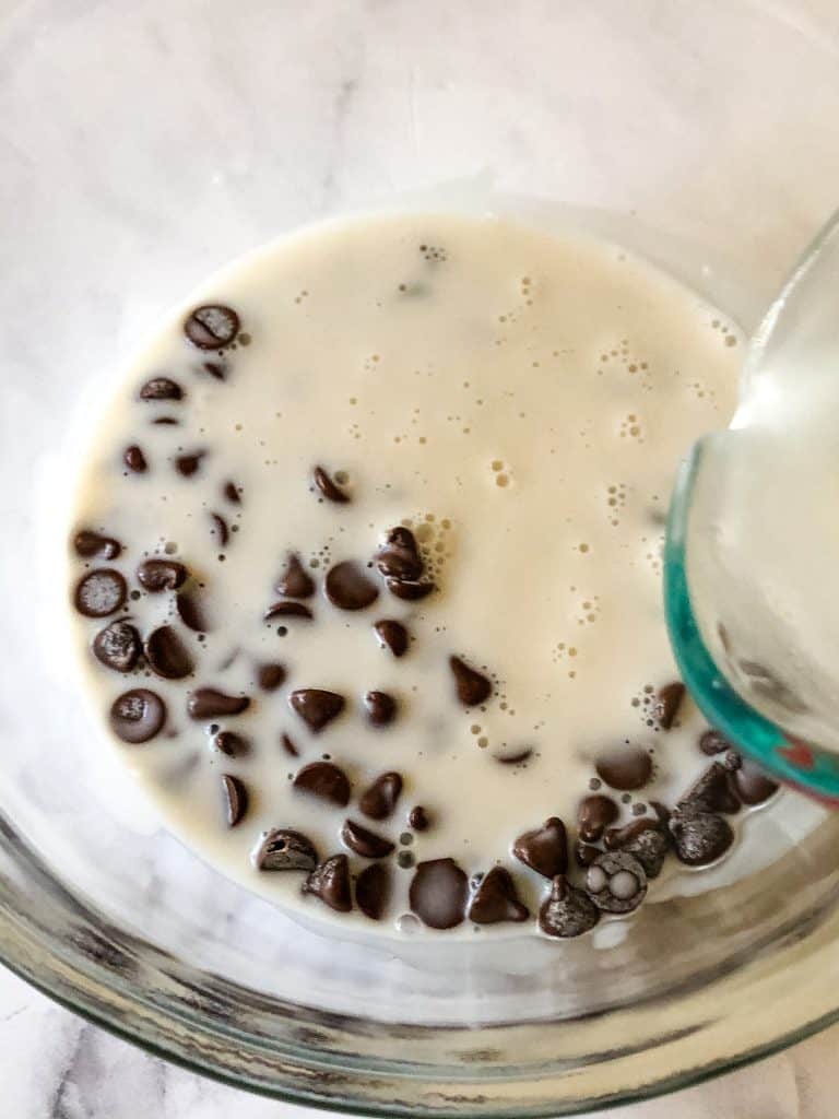 pouring hot coconut cream into the chocolate chips